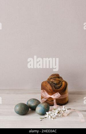Blooming apple tree branch and Easter cake, painted with eggs on the table Stock Photo