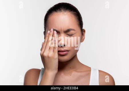 Upset asian woman suffering from strong eye pain Stock Photo