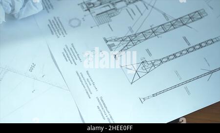 overhead view of architect's desk with blueprints and computer. Top view of a working desk: laptop, glasses, mobile phone, pen, architect drawing, clo Stock Photo