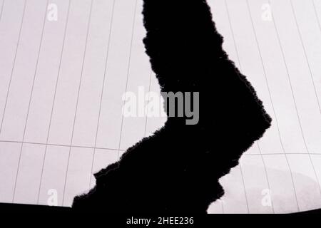 Torn lined white sheet on black Stock Photo