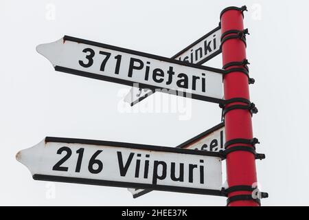 Red signpost, directional signs with distances to destination cities in Finnish. Savonlinna, Finland Stock Photo