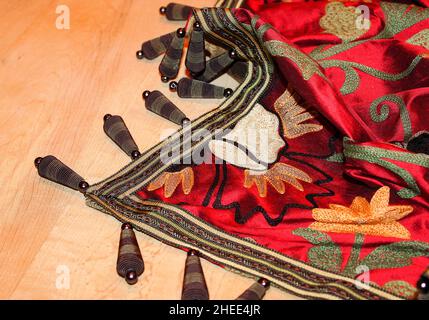 Embroidered richly colored throw with unique bangles artfully displayed on wood background Stock Photo