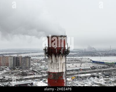 Filmed from drone, from bird's eye view. Thick smoke comes from an industrial chimney of heating station. Ecological problems of big city. Environment Stock Photo