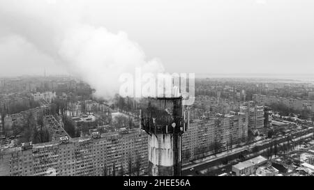 Filmed from drone, from bird's eye view. Thick smoke comes from an industrial chimney of heating station. Ecological problems of big city. Environment Stock Photo