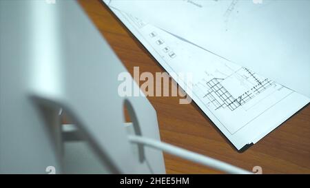 overhead view of architect's desk with blueprints and computer. Top view of a working desk: laptop, glasses, mobile phone, pen, architect drawing, clo Stock Photo