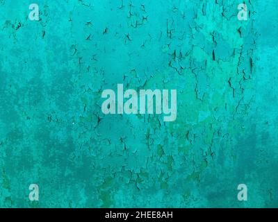Weathered cyan coloured wall, abstract backdrop, cracked paint on the concrete surface. Stock Photo