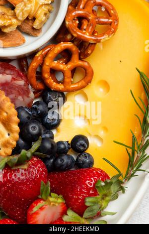 Top view of tasty charcuterie plate with assorted cheese and nuts served with ripe strawberries on table in light kitchen Stock Photo