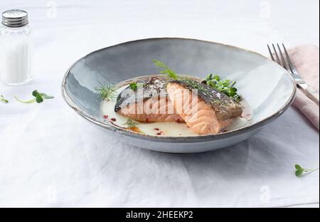 From above delicious salmon with mashed potatoes with green leaves and seasonings on ceramic plate on table Stock Photo