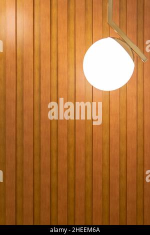 Luminous round lamp on metal hanger hanging against plank wooden wall and decorating room Stock Photo