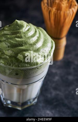 Glass of fresh dalgona coffee with matcha and Japanese tea ceremony accessories consisting of bamboo whisk called chasen placed on gray surface Stock Photo