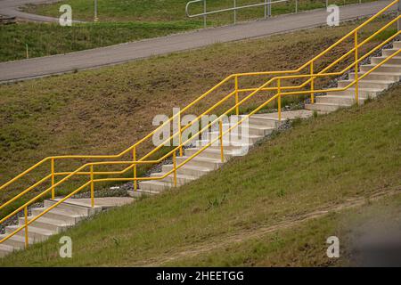 Yellow railings and stairs by a field Stock Photo