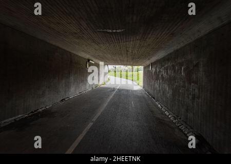 A dark bike underpass with a curve in the end of the tunnel Stock Photo