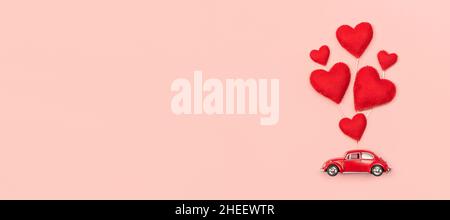 Valentines Day and Mother Day background. Red hearts and retro car on pink background. Stock Photo