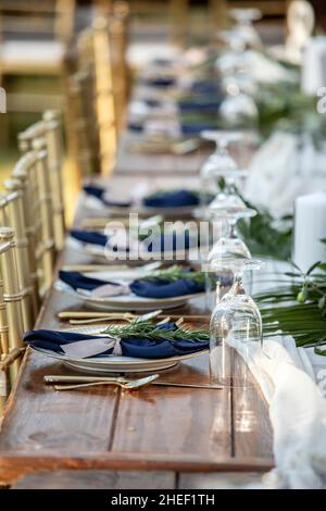 Elegant table set up for outdoor wedding reception with fine china and blue napkins Stock Photo
