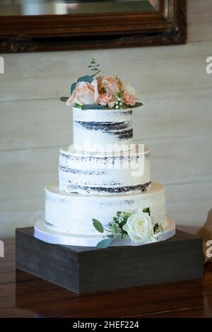 Beautiful three tiered wedding cake with roses and dirty icing, Stock Photo