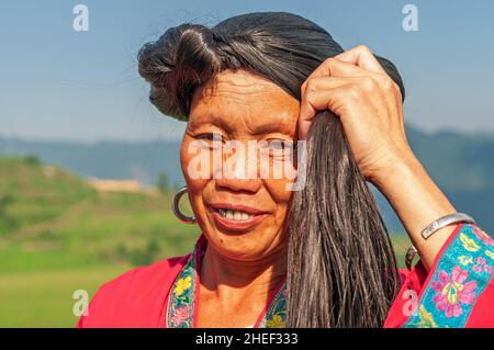 Smiling long haired woman portrait of Yao ethnic group by the Longsheng Ping An rice terraces, Guangxi province, China. Stock Photo