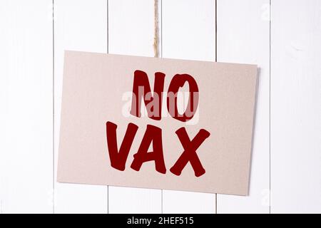 a sign with the words No Vax hanging on a wooden wall Stock Photo