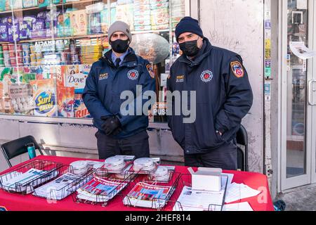 Members of FDNY distribute free literature and smoke alarms on the site of deadly fire caused by malfunctioned space heater claimed 17 lives including 8 children in the Bronx in New York on January 10, 2022. Fire started in the bedroom of the 3rd floor apartment and when residents left their place with the door opened, smoke quickly spread all away to the 15th floor resulting in injuries and death. That apartment door wasn't functioning properly and did not close automatically after residents from the apartment where the fire started escaped. Many were injured and are being treated in local ho Stock Photo