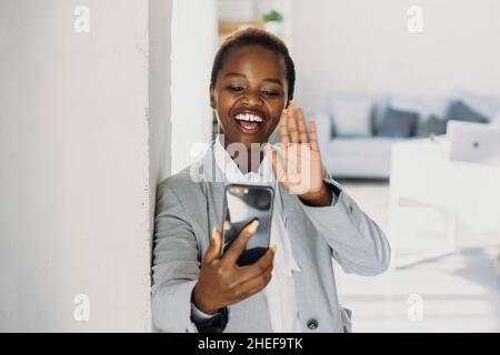 African american businesswoman talking and greeting people on video call on ssmartphone. Stock Photo
