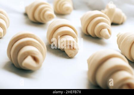 Semifinished or unbaked croissant on a baking sheet. Puff pastry baking. Close up. Stock Photo