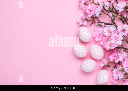 Easter template with paschal eggs and cherry blossom, greeting card with copy space, pastel pink background. Spring season. Christian tradition concep Stock Photo