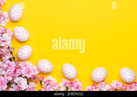 Easter template with paschal eggs and cherry blossoms, gift card with copy space, bright yellow background, frame. Spring season. Christian tradition