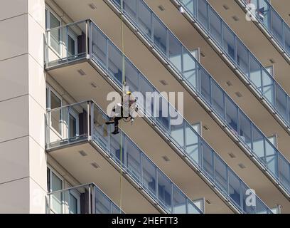 A man cleaning windows on a high rise building in White Rock BC, Canada-October 22,2020. Street view, photo from bottom, selective focus Stock Photo
