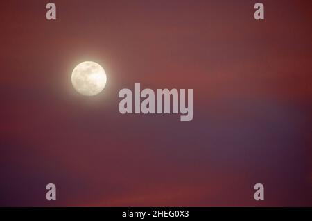 Full moon and colorful clouds at sunset Stock Photo