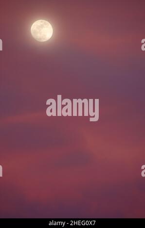 Full moon and colorful clouds at sunset Stock Photo