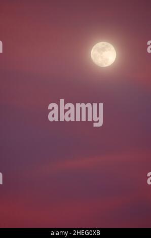 Full moon and colorful clouds at sunset Stock Photo