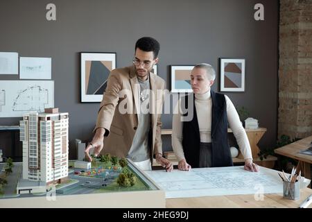 Two professional engineers and architects discussing house layout while one of them making presentation of new project Stock Photo