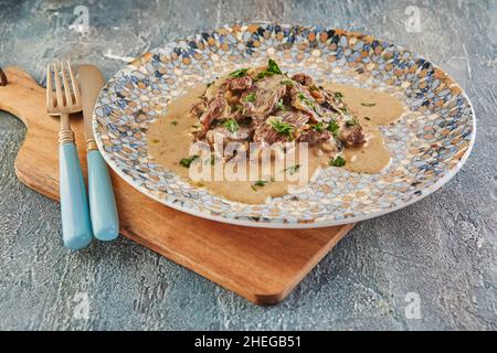 Beef stroganoff on a plate and eating utensils. French gourmet cuisine Stock Photo