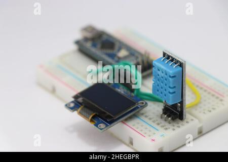 DHT11 or Temperature and humidity sensor with OLED display circuit on a breadboard run by some microcontroller on the background Stock Photo