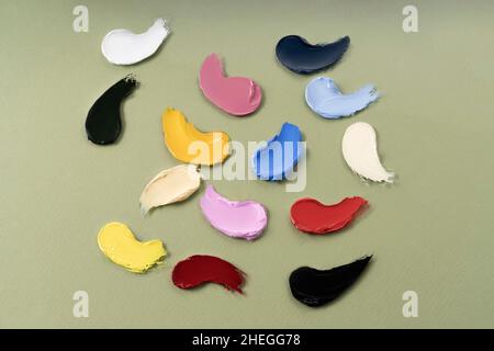 Smears of different colors are made with various cosmetic products or oil paint. On a green background. Texture of multi-colored strokes. Stock Photo