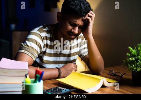 Young student suffering understanding from book while reading or studying for examination - concept of confusion, weak phonemic awareness and Stock Photo