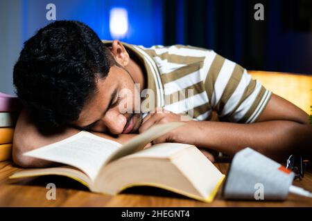 Young student sleeping on table due to taired of reading for examination at home - concept of hard working, lazyiness and late night studying Stock Photo