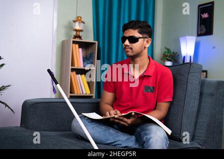 Blind young man reading by touching book at home - concept of education, self development and learning Stock Photo