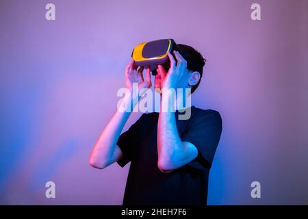 Young man in VR helmet watching in virtual reality, neon colors. Stock Photo