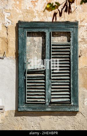 old green weathered wooden window frame with some slats missing Stock Photo