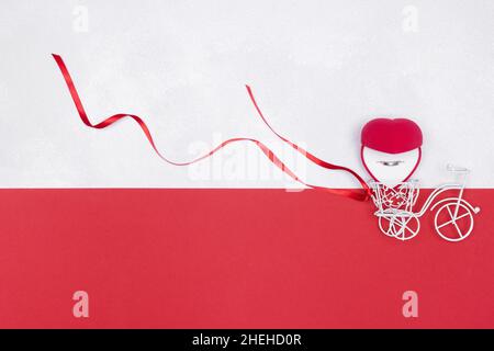 Small white toy bicycle and open red velvet heart shaped gift box with wedding ring. Copy space Stock Photo