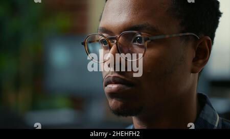 Focus on moving eyes of software developer writing code in front of monitor working focused looking at computer screen. Portrait of software developer with glasses reading algorithm. Stock Photo