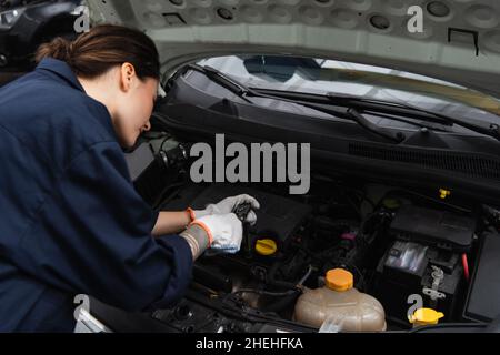 Mechanic working with car engine in garage Stock Photo