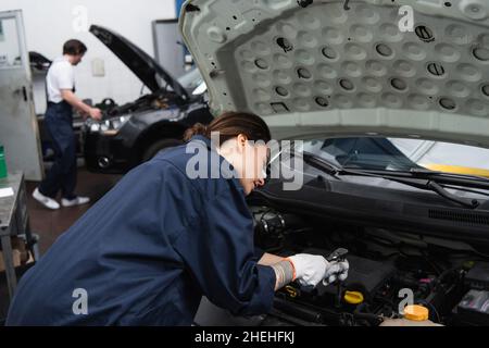Forewoman working with car engine in garage Stock Photo