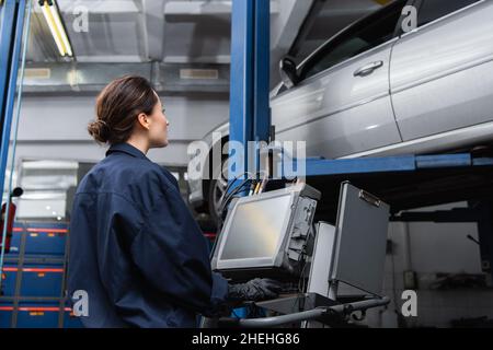 Side view of workwoman using computer near car in service Stock Photo