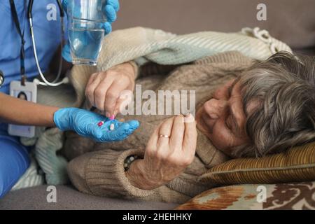 A young nurse is caring for an elderly 80-year-old woman at home. Stock Photo