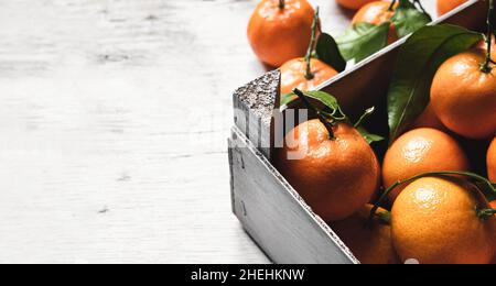 A box with fresh tangerines on on a white wooden table with copy space Stock Photo