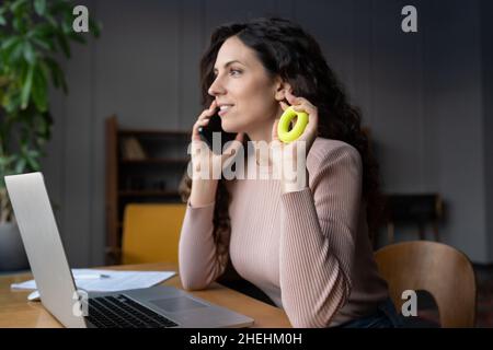 Young businesswoman doing hand warmup exercises at workplace, exercising with grip strengthener ring Stock Photo