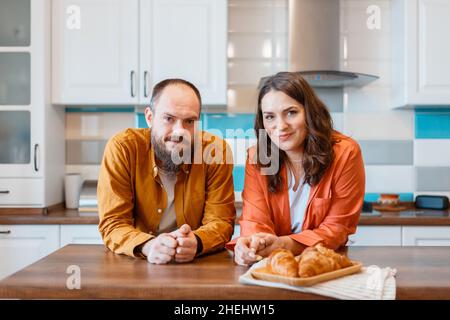 Happy young couple talking at home in kitchen. Family Husband and wife enjoying spending time together while standing in apartment interior. family Stock Photo