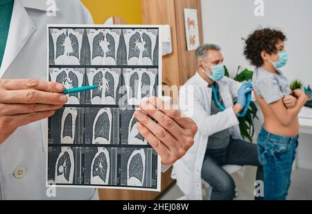 Auscultation of lungs and respiratory system. Pediatrician listening to boy's lungs using a stethoscope. Pulmonologist showing CT scan of lungs in for Stock Photo