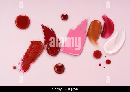 Smears of different colors are made with various cosmetic products. On a pink background. Texture of multi-colored strokes. Stock Photo